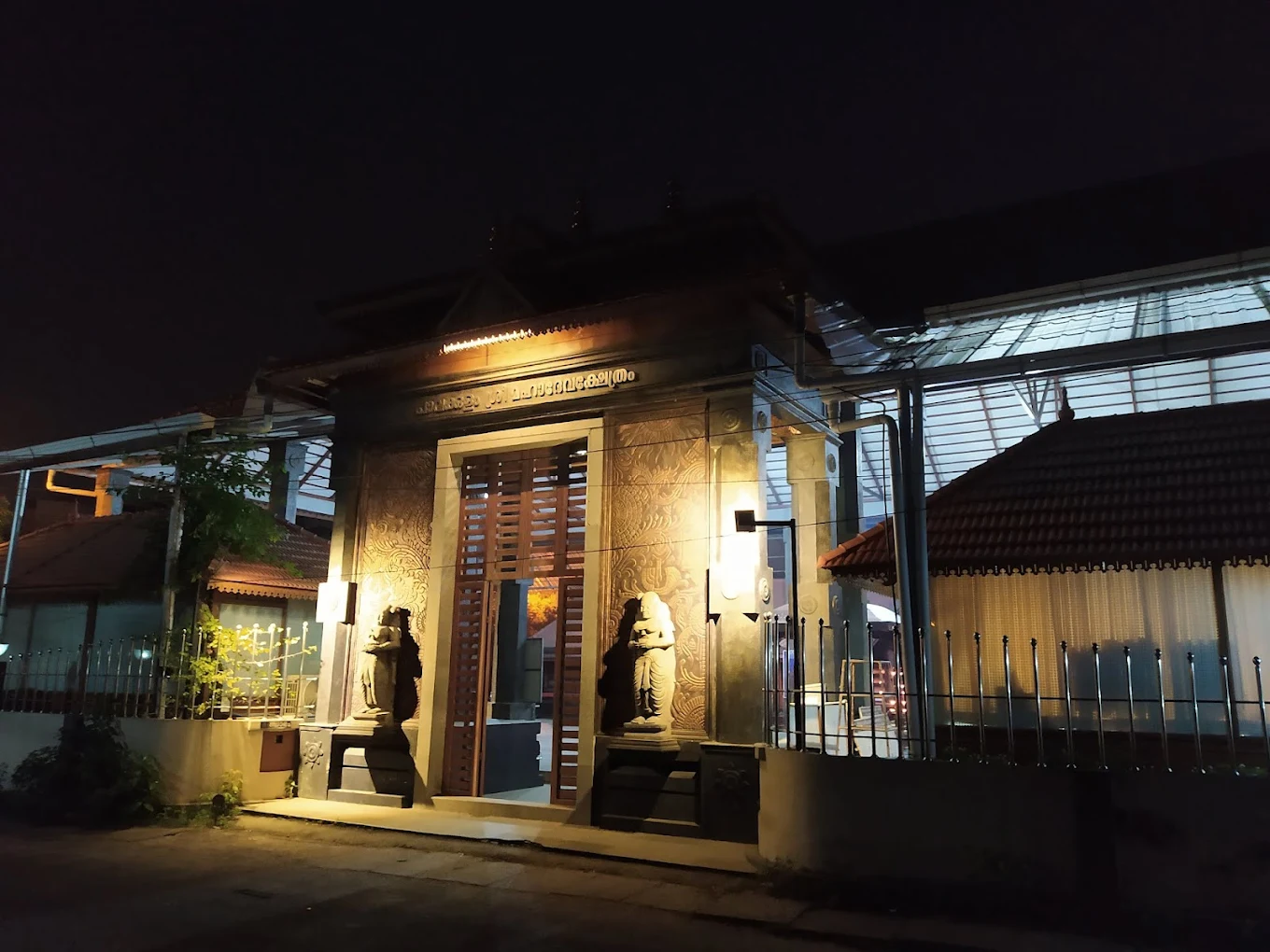 Entrance of Pavakulam Sree Mahadeva Temple showcasing intricate wood carvings and temple tower
