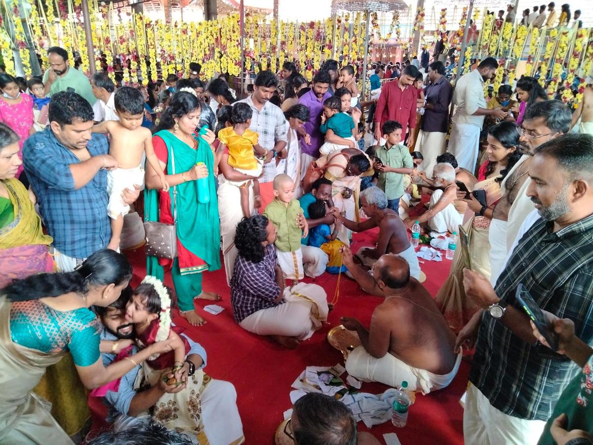 Children performing first writing during Vidyarambham at Kizhakkedath Daivathum Parambu Temple